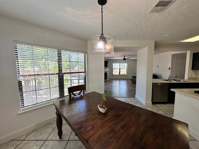 tiled dining space featuring sink, ceiling fan, and a textured ceiling