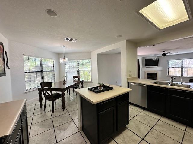 kitchen featuring a center island, sink, dishwasher, and light tile floors