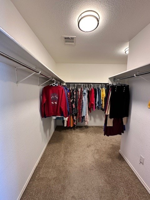 walk in closet featuring dark carpet