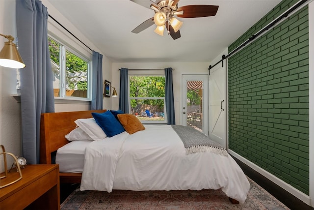 bedroom with ceiling fan, a barn door, and multiple windows