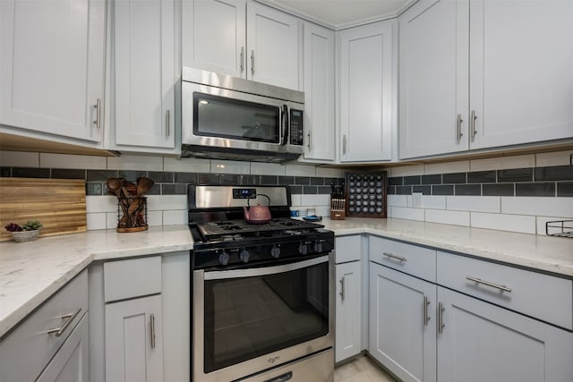 kitchen with light stone countertops, tasteful backsplash, and appliances with stainless steel finishes