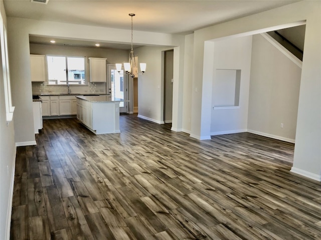 kitchen with an inviting chandelier, a center island, decorative light fixtures, dark hardwood / wood-style floors, and white cabinets