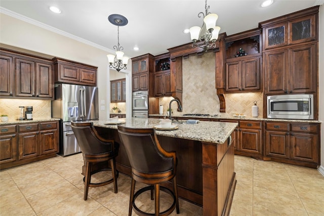 kitchen featuring an inviting chandelier, appliances with stainless steel finishes, pendant lighting, and a kitchen island with sink