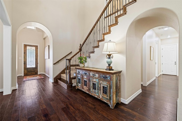 foyer featuring a towering ceiling and dark wood-type flooring