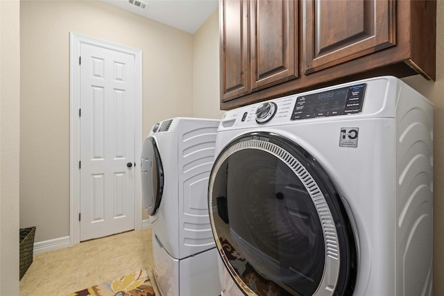 laundry room with cabinets, light tile floors, and washing machine and clothes dryer