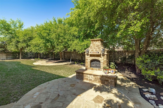 view of yard featuring a patio area and an outdoor stone fireplace