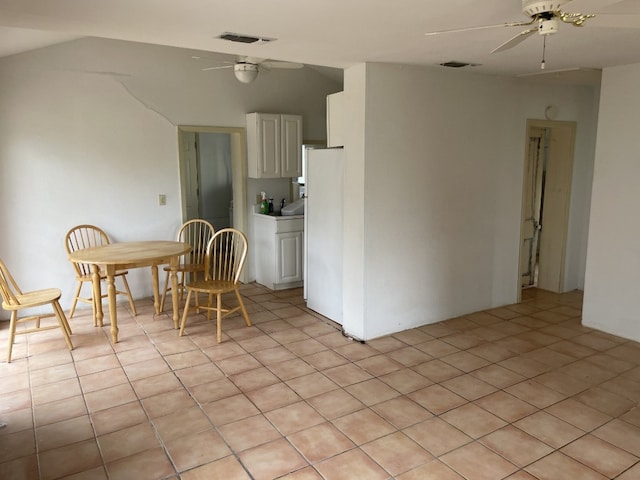 interior space with light tile floors, white cabinets, white fridge, and ceiling fan