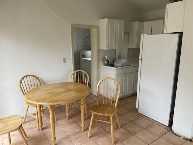 tiled dining space featuring washer / dryer, sink, and vaulted ceiling