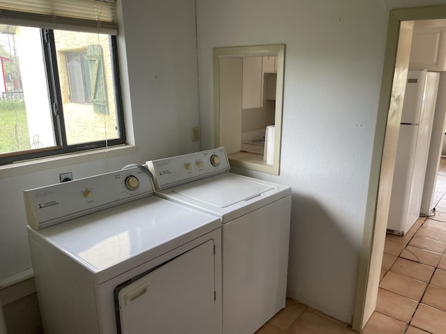 laundry room featuring light tile flooring, separate washer and dryer, and a healthy amount of sunlight