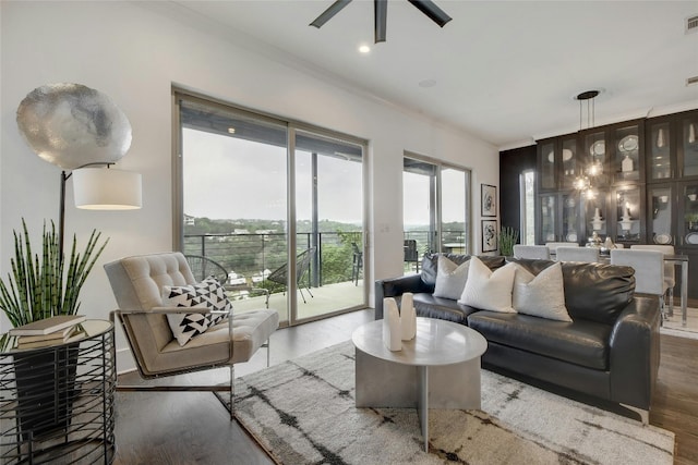 living room with crown molding, dark wood-type flooring, and ceiling fan