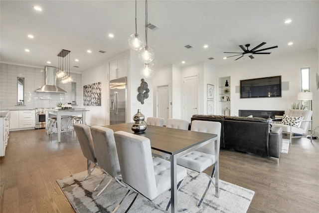 dining area with built in features, light hardwood / wood-style flooring, and ceiling fan