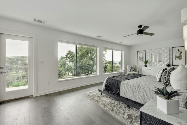 bedroom with access to outside, multiple windows, visible vents, and wood finished floors