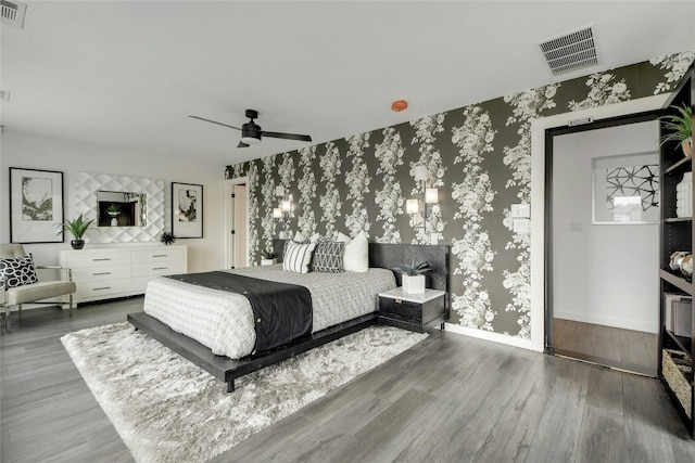 bedroom featuring wallpapered walls, baseboards, visible vents, and wood finished floors