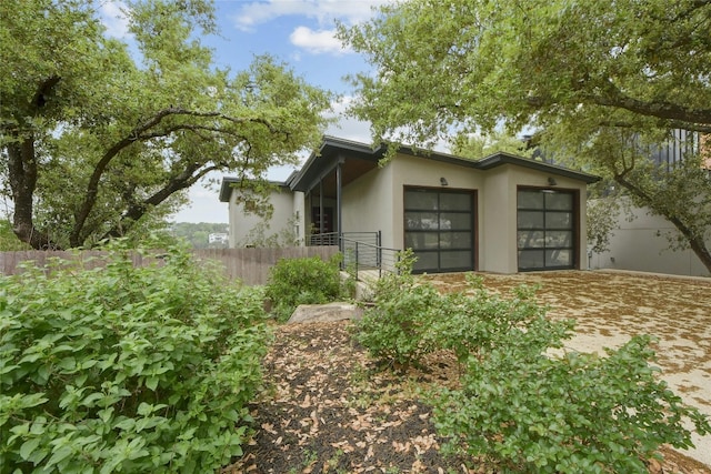 view of side of home with an attached garage, fence, and stucco siding