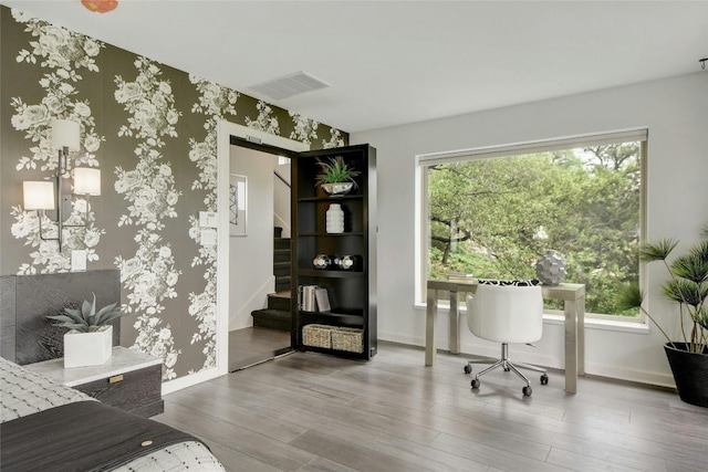 office space featuring baseboards, visible vents, wallpapered walls, and wood finished floors