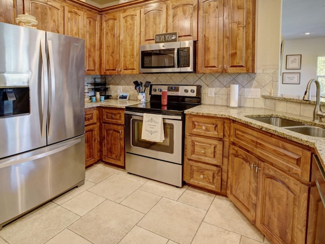 kitchen featuring a sink, light stone counters, appliances with stainless steel finishes, and light tile patterned floors