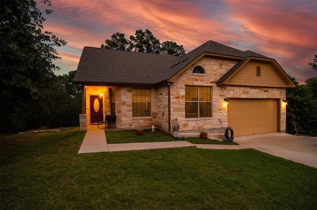 view of front of house featuring a lawn, an attached garage, driveway, and roof with shingles