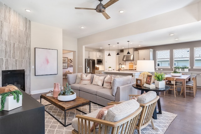 living room with ceiling fan, dark hardwood / wood-style flooring, and a tiled fireplace