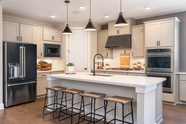 kitchen with a center island with sink, dark hardwood / wood-style flooring, a breakfast bar area, and appliances with stainless steel finishes