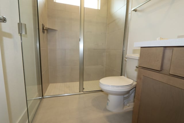 bathroom with tile patterned flooring, vanity, toilet, and a shower with shower door