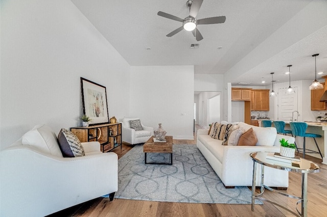 living room featuring sink, ceiling fan, and light hardwood / wood-style flooring