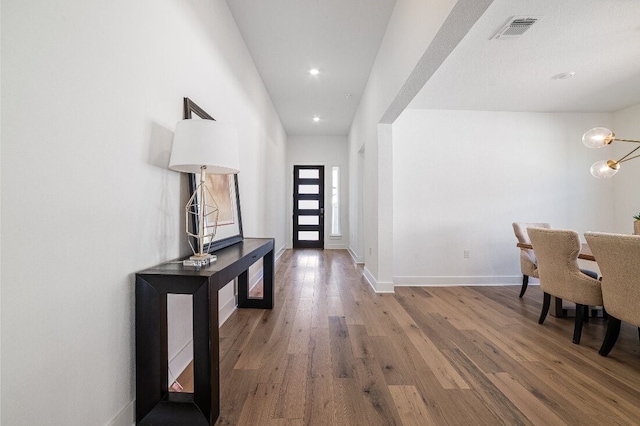 foyer entrance featuring wood-type flooring and a chandelier