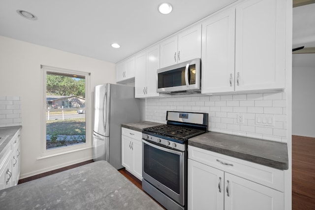 kitchen featuring decorative backsplash, white cabinetry, dark hardwood / wood-style floors, and appliances with stainless steel finishes