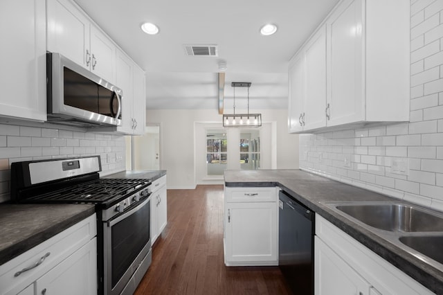 kitchen with decorative light fixtures, stainless steel appliances, white cabinetry, and dark hardwood / wood-style floors