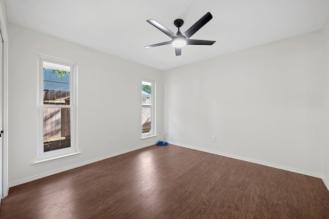 spare room with ceiling fan, a healthy amount of sunlight, and dark wood-type flooring