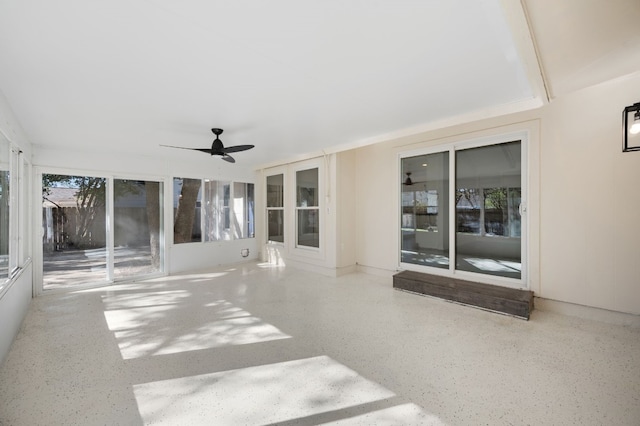 unfurnished sunroom featuring ceiling fan and a healthy amount of sunlight