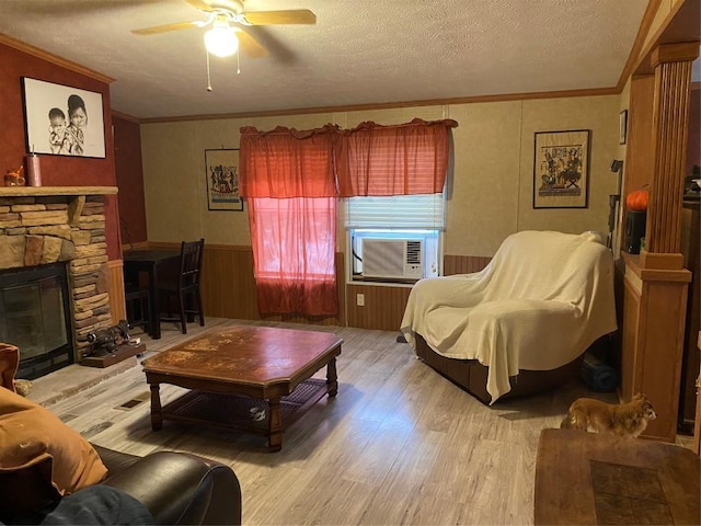 living room featuring light wood-style floors, wainscoting, crown molding, and a textured ceiling