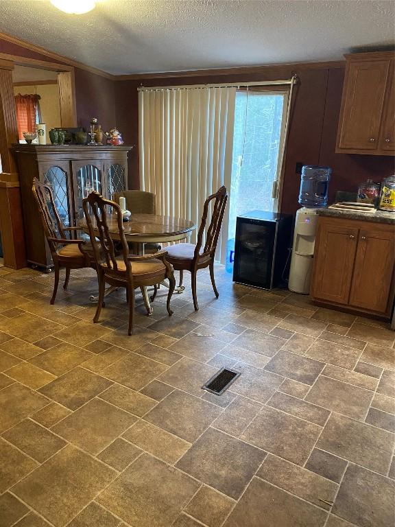 dining room featuring a textured ceiling, ornamental molding, stone finish floor, and visible vents