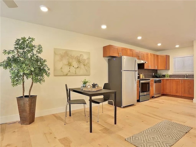 kitchen with light hardwood / wood-style flooring, appliances with stainless steel finishes, tasteful backsplash, and sink