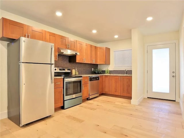 kitchen featuring tasteful backsplash, stainless steel appliances, sink, and light hardwood / wood-style flooring