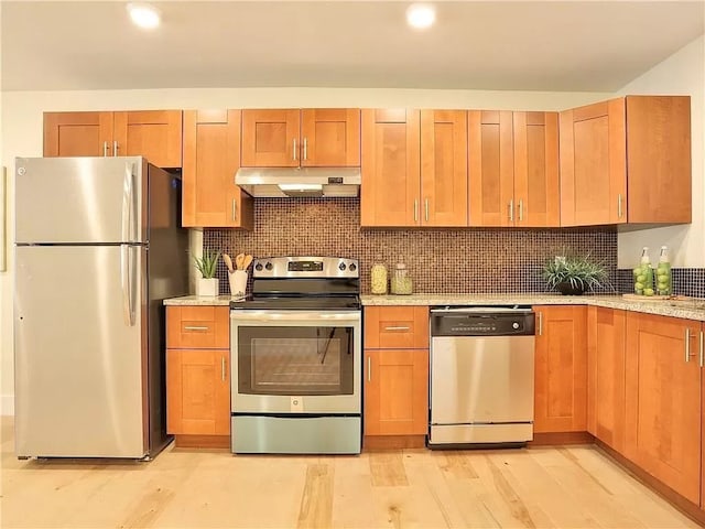 kitchen featuring light hardwood / wood-style flooring, light stone countertops, stainless steel appliances, and tasteful backsplash