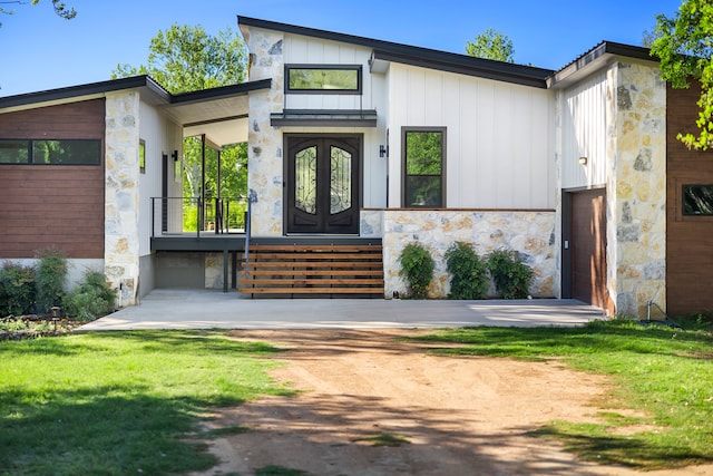 view of front of house featuring a garage, a front lawn, and french doors