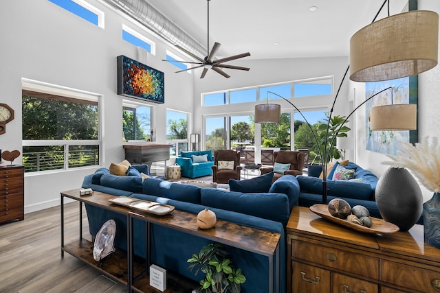 living room featuring ceiling fan, plenty of natural light, a towering ceiling, and wood-type flooring