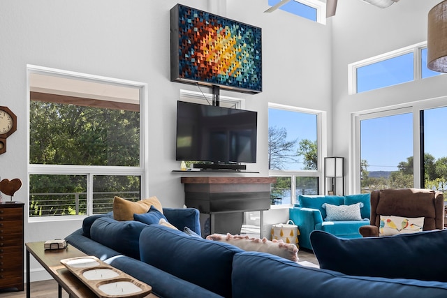 living room with wood-type flooring, a wealth of natural light, and a high ceiling