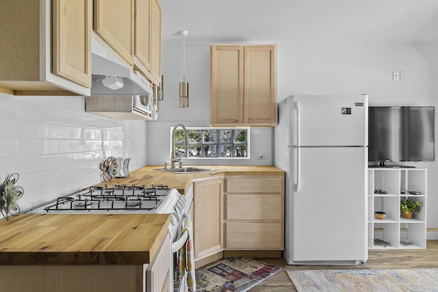 kitchen featuring wooden counters, light brown cabinetry, stainless steel gas stove, white refrigerator, and sink