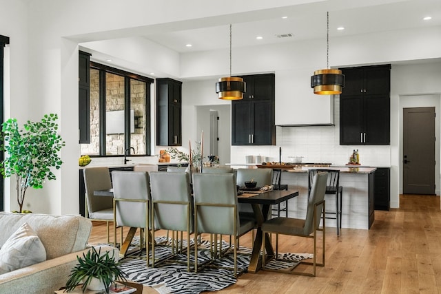 kitchen featuring hanging light fixtures, backsplash, a breakfast bar area, a kitchen island, and light hardwood / wood-style floors