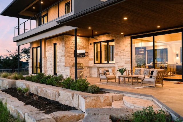 patio terrace at dusk featuring an outdoor living space and a balcony