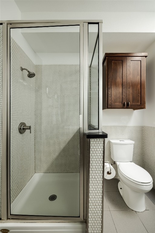 bathroom featuring tile patterned floors, a shower with shower door, tile walls, and toilet