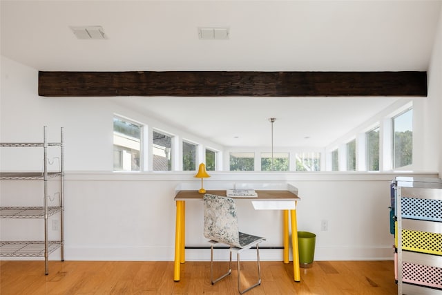 interior space with beamed ceiling, a wealth of natural light, and light hardwood / wood-style flooring