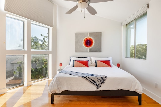 bedroom featuring access to exterior, light wood-type flooring, multiple windows, and ceiling fan