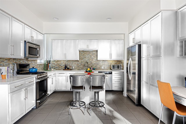 kitchen with white cabinetry, stainless steel appliances, a breakfast bar area, and tasteful backsplash