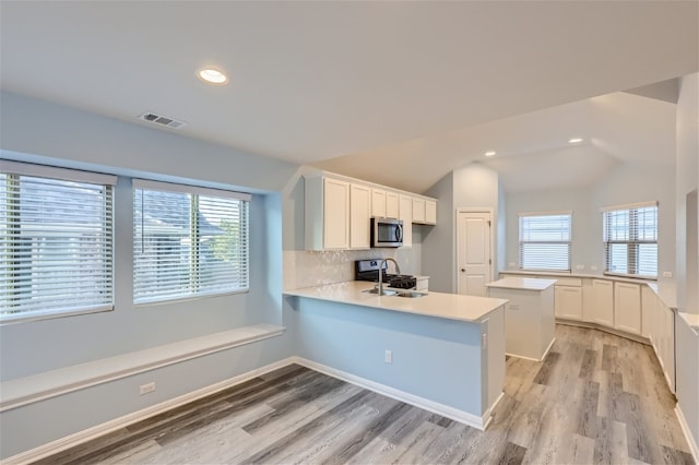 kitchen with plenty of natural light, stainless steel appliances, light wood-type flooring, and white cabinetry