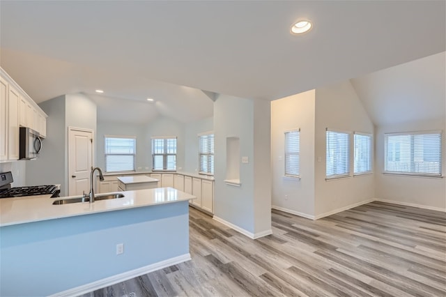 kitchen featuring light hardwood / wood-style flooring, sink, vaulted ceiling, and stove