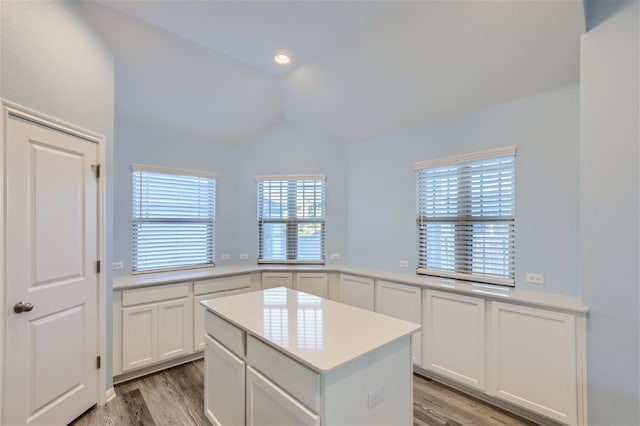 kitchen featuring lofted ceiling, light wood-type flooring, a center island, and white cabinetry