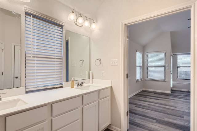 bathroom featuring dual sinks, lofted ceiling, large vanity, and wood-type flooring