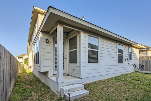 view of side of property with a lawn and central AC